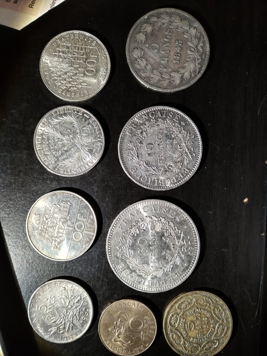 Neuf monnaies françaises en argent posées sur fond noir