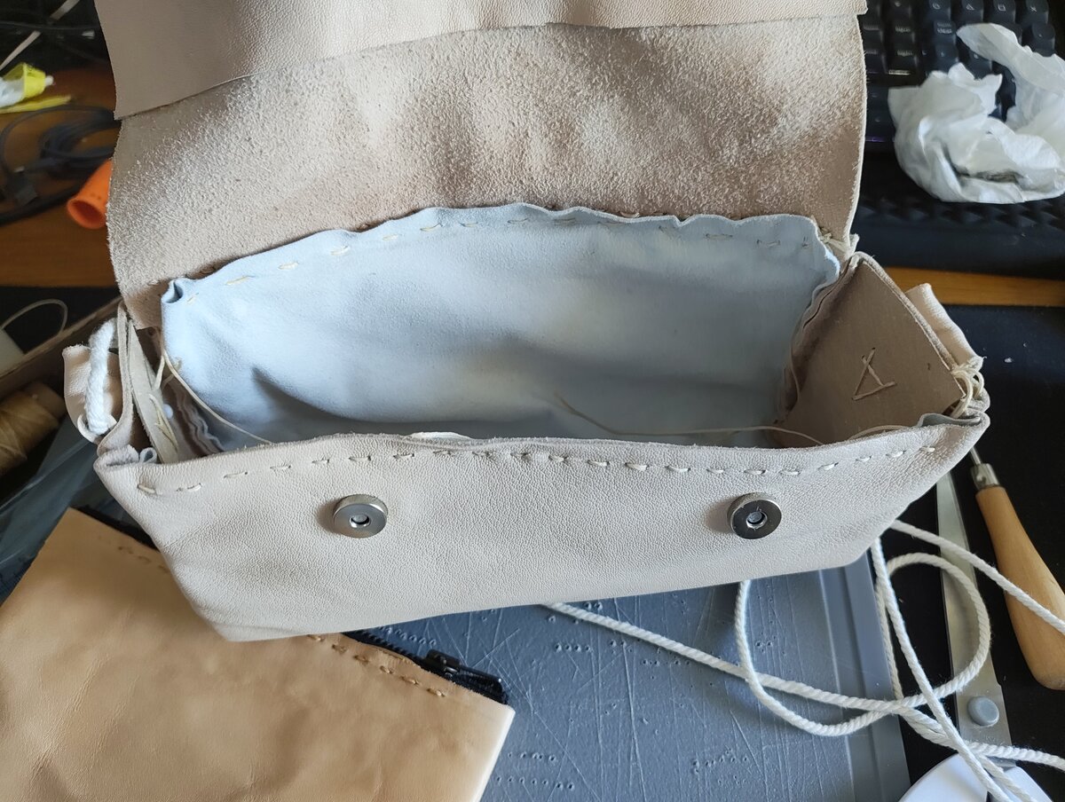 Petit sac à bandoulière en cuir naturel ouvert montrant la doublure et les pressions